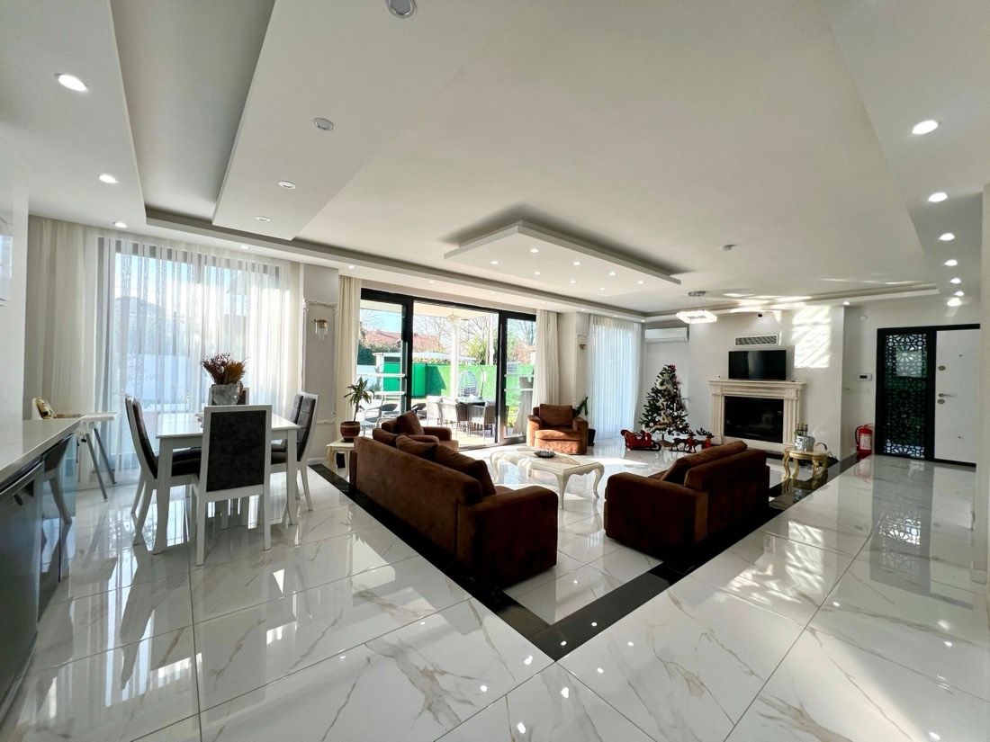 Şömineli geniş salon, yemek alanı ve bahçeye açılan cam kapılar
